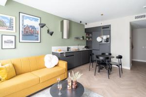 een woonkamer met een gele bank en een tafel bij YAYS Antwerp Opera by Numa in Antwerpen