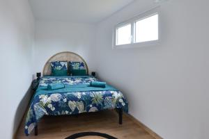 a bedroom with a bed with a blue bedspread at Le Guillaume - Sauna - A moins de 2 km de la plage in Sainte-Honorine-des-Pertes