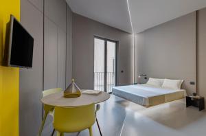 una camera con letto, tavolo e TV di Fiveplace Design Suites & Apartments a Trapani