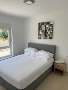 - une chambre avec un lit doté de draps blancs et une fenêtre dans l'établissement The Palms Luxury Pool Aparthotel, à Novalja