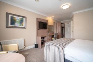 a hotel room with a bed and a tv at Corr's Corner Hotel in Newtownabbey