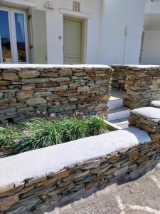 a stone retaining wall in front of a house at Altana Boutique Hotel in Tinos Town