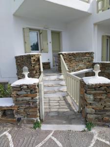 a house with a stone wall and a stairway at Altana Boutique Hotel in Tinos Town