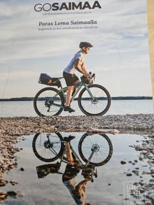 un hombre montando una bicicleta en la playa con su reflejo en Saimaa Marina Garden Apartments, en Lappeenranta