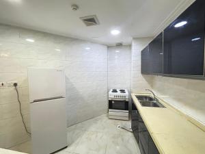 a kitchen with a white refrigerator and a sink at Al Hayat Suites Apartment in Manama