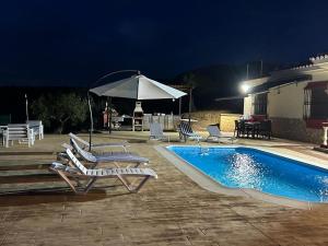 a swimming pool with lounge chairs and an umbrella at Casa Rural Alora Caminito del Rey in Alora