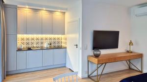 a kitchen with white cabinets and a table with a television at Apartamenty Dudek - stylowe apartamenty, 5 minut pieszo do morza! in Rowy