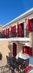 a table and chairs in front of a building with red shutters at VILLA ELENA in Halki