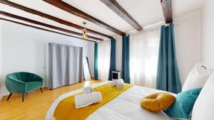 a bedroom with a large bed and a green chair at Triplex Le Bel Âtre in Sélestat