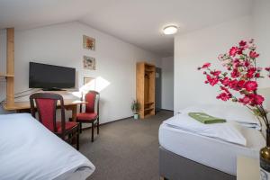 ein Hotelzimmer mit 2 Betten, einem Schreibtisch und einem TV in der Unterkunft Hotel u Budvaru in Budweis