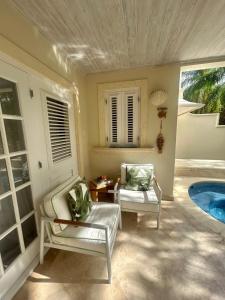 a living room with two chairs and a pool at Shimmers, stunning, stylish West Coast Villa in Saint Peter