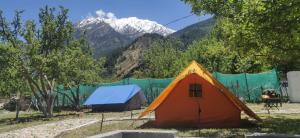 tenda in un campo con montagne sullo sfondo di Hinwali Kanthi River Side Camp and Cottage a Harsil
