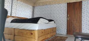 una persona sdraiata su un letto in una stanza di Hinwali Kanthi River Side Camp and Cottage a Harsil