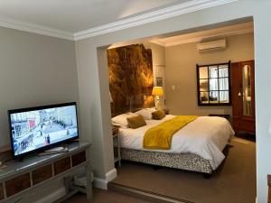 a bedroom with a bed and a flat screen tv at La Pension Guest House in Oudtshoorn