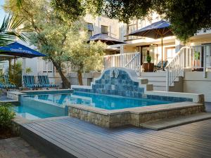 a swimming pool with stairs and blue chairs and umbrellas at Protea Hotel by Marriott Dorpshuis & Spa Stellenbosch in Stellenbosch