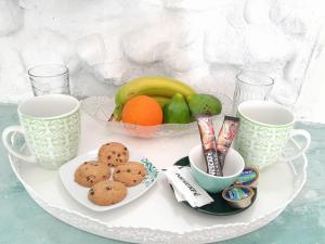 einen Teller mit Keksen und Obst und zwei Tassen in der Unterkunft Lavish Sunset Suite Arkasa in Arkasa
