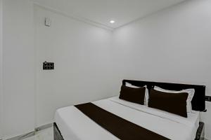 um quarto branco com uma cama com almofadas pretas e brancas em OYO 82287 Hotel Dream 1 Inn em Rāipur