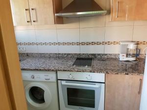 una cocina con estufa horno superior junto a una lavadora en BRAVAHOLIDAYS-110-Kristel-6-33, en Blanes