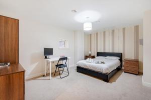 a bedroom with a bed and a desk and a television at The Railway Pass The Keys Modern 2-Bed Apartment in Central Altrincham in Altrincham