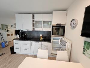 a white kitchen with white cabinets and white chairs at Ostseefalter 1 in Graal-Müritz