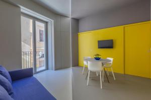 Fiveplace Design Suites & Apartments في تراباني: غرفة معيشة مع طاولة وجدار اصفر