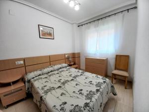 ein Schlafzimmer mit einem Bett, einem Schreibtisch und einem Stuhl in der Unterkunft Costa Azahar II Nº 1041 in Oropesa del Mar