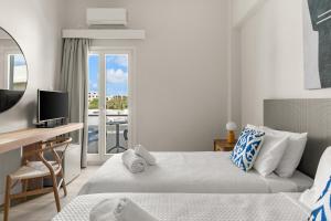 1 dormitorio con 2 camas, escritorio y balcón en Paradise Art Hotel, en Ándros