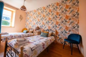 a bedroom with two beds and a wall covered in flowers at Gite L'Orangerie du Château D'Emalleville in Émalleville