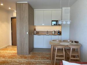 a kitchen with white cabinets and a table and stools at BEL MARE 2 F207 in Międzyzdroje +11 photos