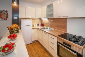 una cocina con electrodomésticos blancos y un bol de fruta en una barra en Apartment & Double Room Stanka, en Baška