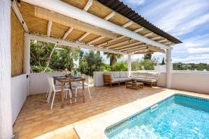 a patio with a table and chairs and a swimming pool at Casa Ladeira in Loulé