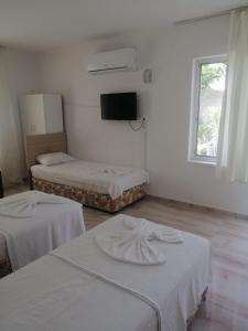 a room with two beds and a television in it at Kiriş Banana Suit in Kemer