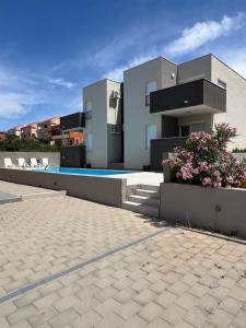 une grande maison blanche avec une piscine dans l'établissement The Palms Luxury Pool Aparthotel, à Novalja