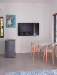 Una sala de estar con una mesa y un televisor en una pared. en Bungalow Baan Joan, en Khao Lak