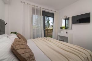 a bedroom with a bed with a television and a window at Sun White Villas in Laganas