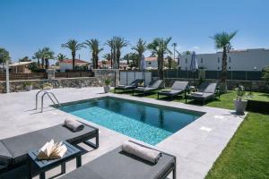 a swimming pool with chaises and chairs next to a yard at SunWhite Villas - Private Pool & Cozy Atmosphere, by ZanteWize in Laganas