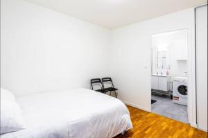 - une chambre blanche avec un lit et deux chaises dans l'établissement Jolie 2 pièces à Aubervilliers, à Aubervilliers