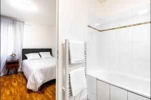 - une chambre blanche avec un lit et une baignoire dans l'établissement Jolie 2 pièces à Aubervilliers, à Aubervilliers