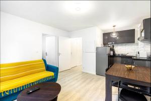un salon avec un canapé jaune et une cuisine dans l'établissement Jolie 2 pièces à Aubervilliers, à Aubervilliers