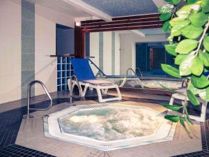 uma banheira de hidromassagem num quarto com uma cadeira em Mercure Epinal Centre em Épinal