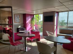 um restaurante com duas mesas e cadeiras e paredes cor-de-rosa em Mercure Epinal Centre em Épinal