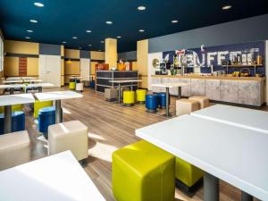 un restaurante con mesas blancas y sillas amarillas en Ibis Budget Graz City en Graz
