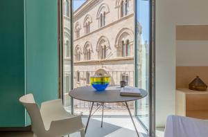 Fiveplace Design Suites & Apartments في تراباني: طاولة عليها وعاء بجوار النافذة