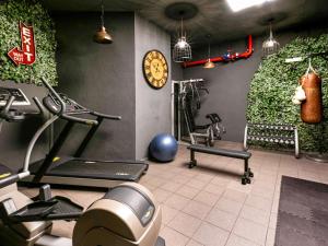 a gym with exercise equipment and a clock on the wall at Novotel Barcelona City in Barcelona