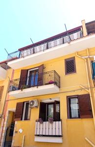 een geel gebouw met balkons en bloemen erop bij La casa di Andrea in Terrasini