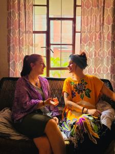 Duas mulheres estão sentadas num sofá. em JWALA JAIPUR em Jaipur