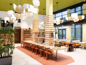 a restaurant with wooden tables and chairs and large columns at Aparthotel Adagio Bordeaux Centre Gambetta in Bordeaux