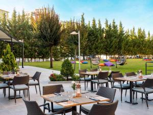 a restaurant with tables and chairs and a park at Novotel Kayseri in Kayseri