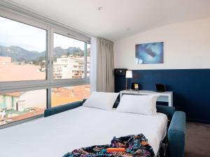 a bedroom with a large bed and a large window at Ibis Styles Menton Centre in Menton
