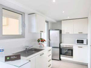 a white kitchen with a sink and a refrigerator at Ibis Styles Menton Centre in Menton